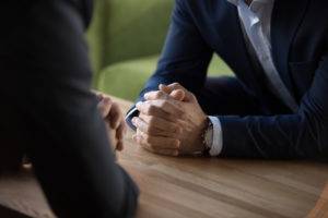 hombres de negocios sentados uno frente al otro con las manos cruzadas